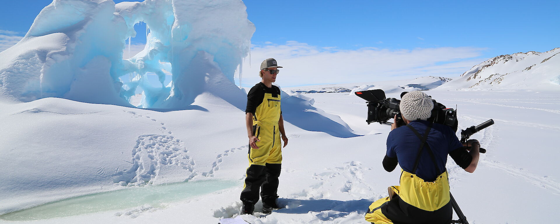 ABC3 presenter Kayne Tremills and cameraman Josh Zaini film a segment for the new Australian children’s television show Antarctica: Secrets of the Giant Freezer, standing in front of an ice formation