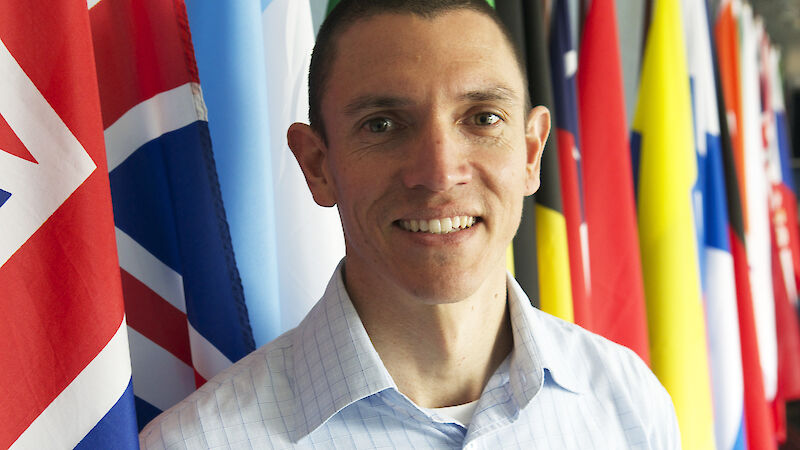 New CEP Chair, Ewan McIvor, standing in front of many nations’ flags