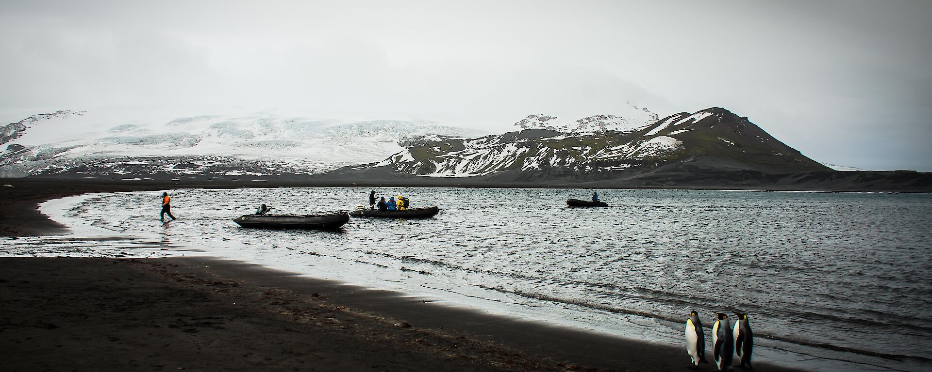 Three small rubber boats ferry tourists to the shores of Heard Island.