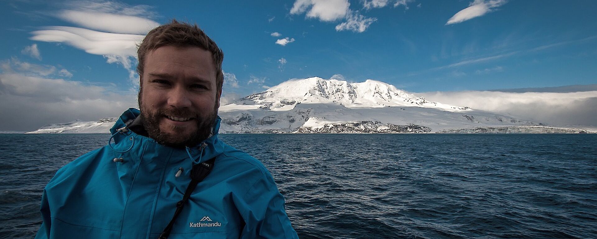 Matt Curnock in a boat with Heard Island in the distance