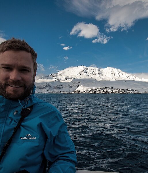 Matt Curnock in a boat with Heard Island in the distance