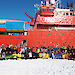 The team of scientists participating in the sea ice voyage standing on the sea ice beside the ship.