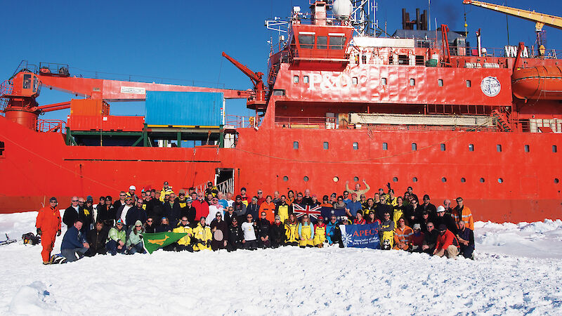 The team of scientists participating in the sea ice voyage standing on the sea ice beside the ship.