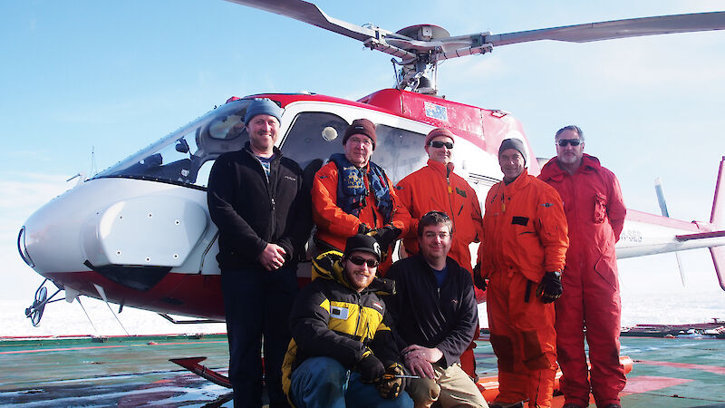 The Antarctic aerial survey team standing beside a helicopter in Antarctica.