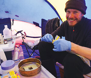 Biologist Paul Czechowski doing preliminary analyses on soil samples in a tent in Antarctica.