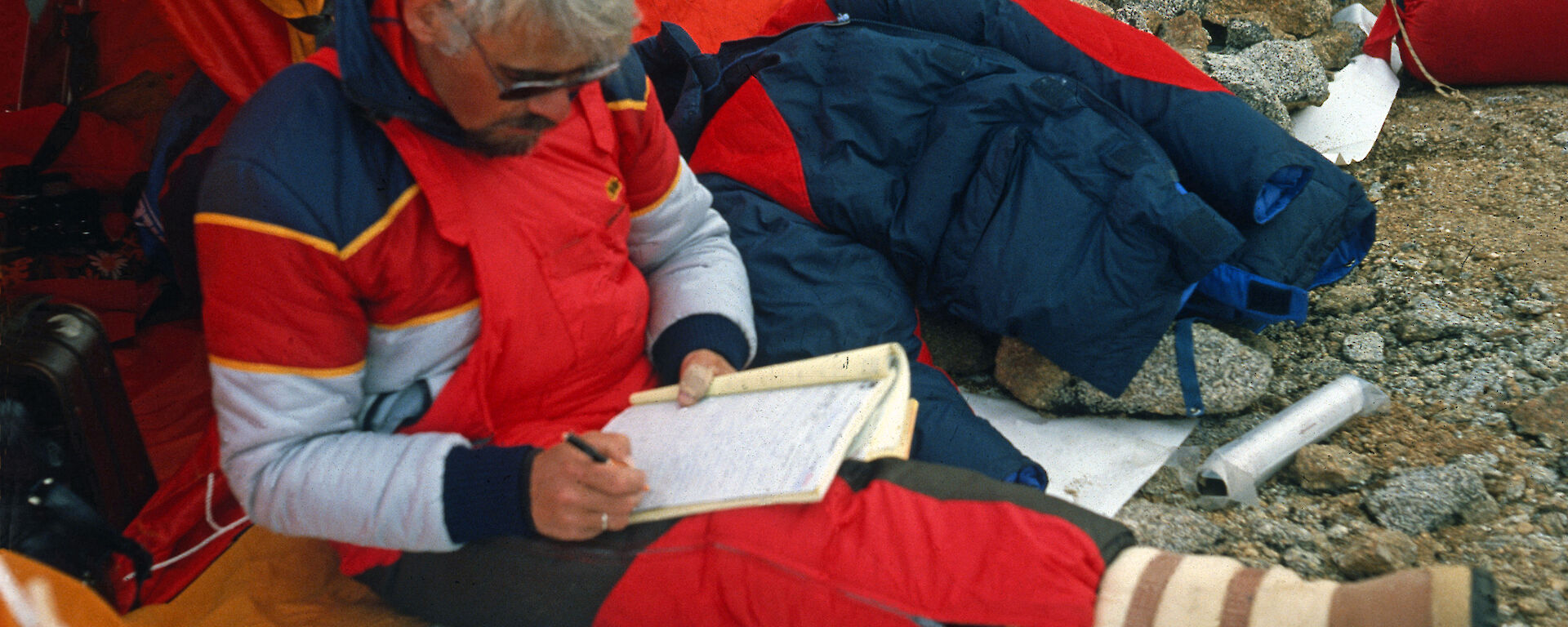 The radio operator Werner Thonhausen of the Gotland II at the entrance of his emergency tent at Birthday Ridge. Werner is still updating his radio log-book and surrounded by the only possessions that he could salvage from the ship after its sinking in December 1981.