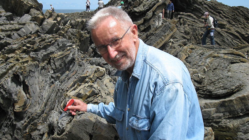 Professor Chris Wilson using the knife on a Specialist Group of Tectonics and Structural Geology field trip at Cape Liptrap, Victoria.