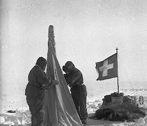 Early expeditioners erecting a tent, with Swiss flag in the background.