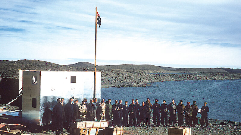 Men gathered around a flag pole on the official opening of Davis station in 1957