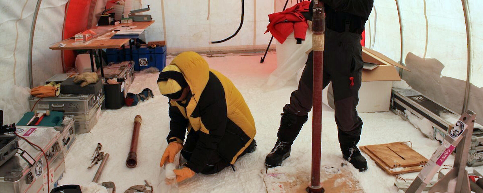 2 ice core scientists working in a drill tent in Antarctica