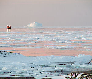 Sunlight reflecting off water and ice with ship and iceberg in background