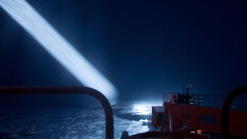A search light beam from the Aurora Australis illuminates the surrounding sea ice and ocean.