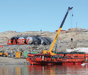 Containers of waste from the Thala Valley tip site are loaded from the Casey wharf on to a barge, for transfer to the Xue Long.