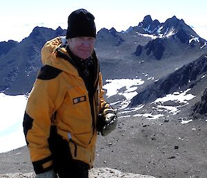 Expeditioner standing on ledge with mountain in background