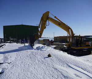 Excavator removing accumulated ice and snow from the selected site