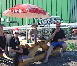 Expeditioners sitting around a picnic table under beach umbrellas