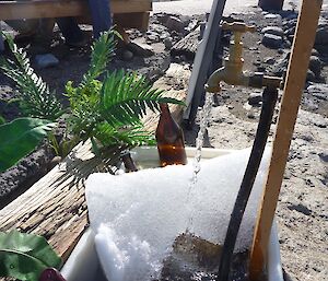 A fish bin as a drinks cooler with ice and a running tap