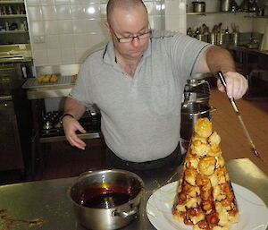 Chef Scott spins toffee syrup onto the pyramid of choux balls