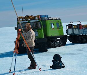 Expeditioner using a Dumpy level to check the alignment of the runway markers