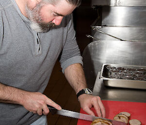 Expeditioner Cotty slicing the duck neck sausage ready for serving