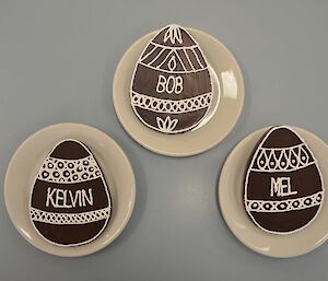 Three chocolate eggs, each with the owner’s name and decoration in white chocolate.