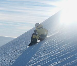 Expeditioner controlling his speed, sliding down a slope using his ice axe