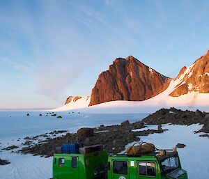 The green Hägglunds all terrain vehicle parked outside Rumdoodle Hut at sunset