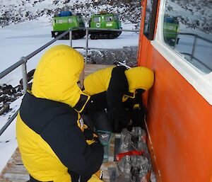 Two expeditioners lighting stoves on the deck outside Hendo Hut