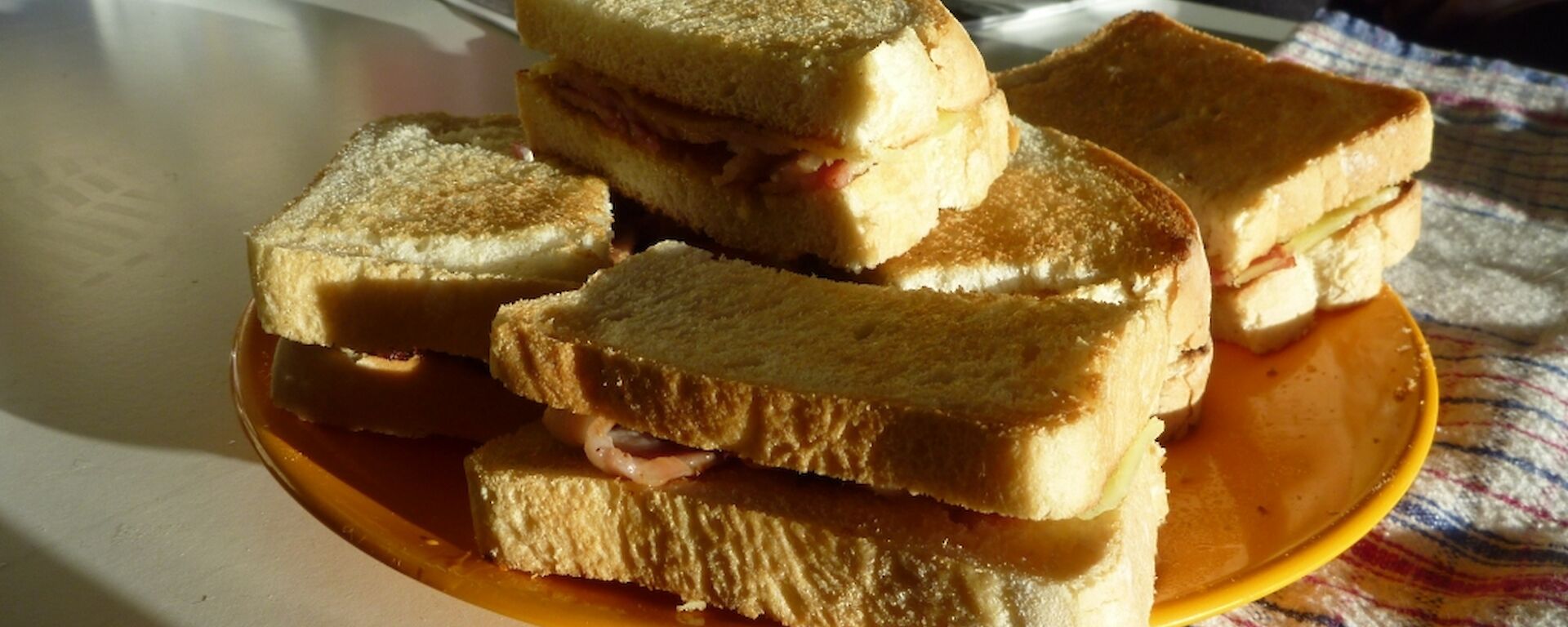 A plate of toasted bacon and cheese sandwiches