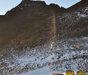 Expedioners standing on the porch of Mt Henderson field hut with the summit in the background