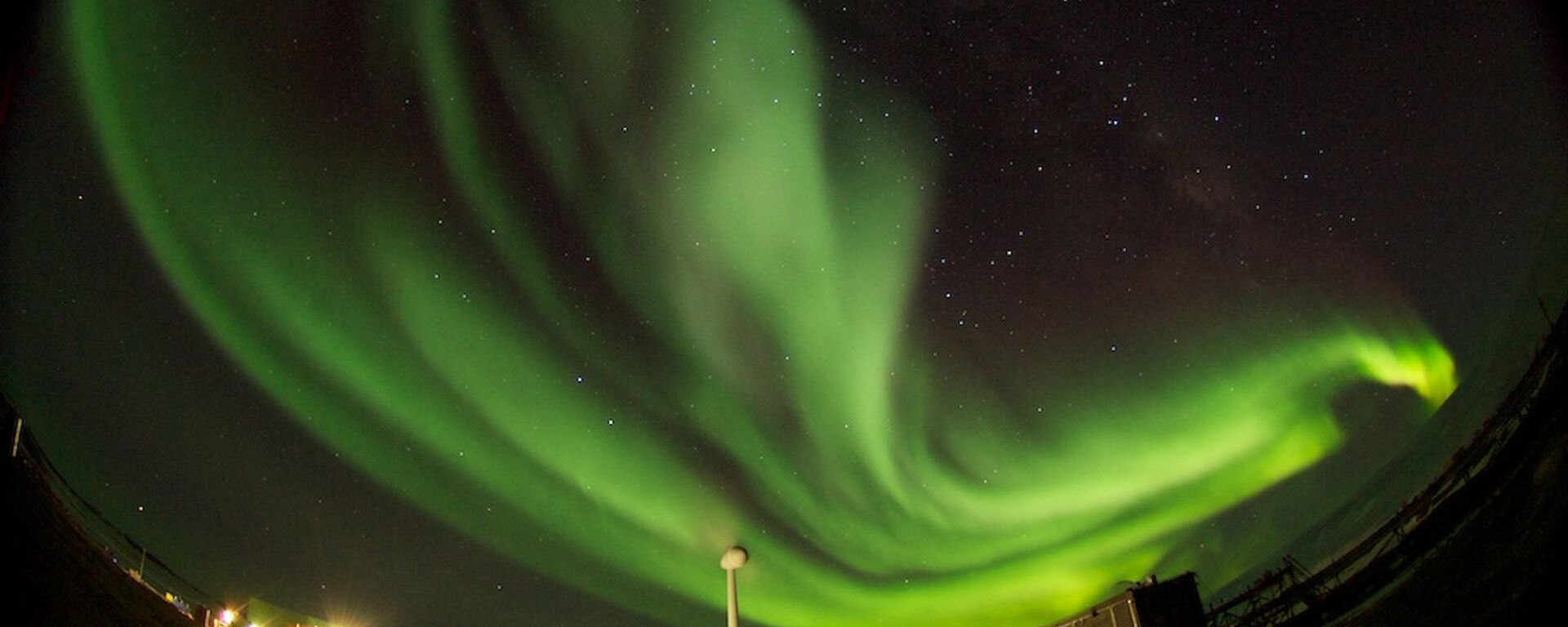 Aurora with wind turbine and buildings in foreground
