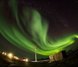 Aurora with wind turbine and buildings in foreground