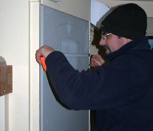 Carpenter measuring the position of the window in the hut door