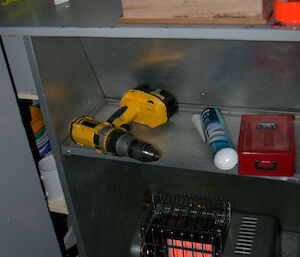 Warming the carpenter’s tools above the heater with the framed window on the bench