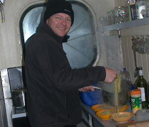 An expeditioners serving the last meal of 2 minute noodles cooked on the old stove