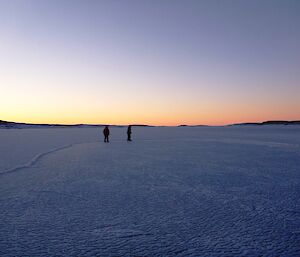 Two skaters on the ice rink at sunset