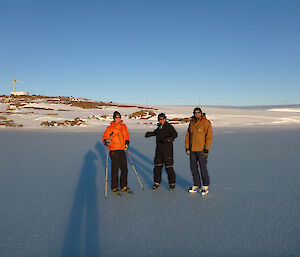 Three skaters one using ski poles on the sea-ice
