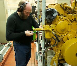An expeditioner changing an oil filter on a gen Set in the power house