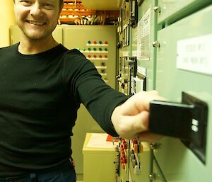 An expeditioner with his hands on one of the main switches in the power house