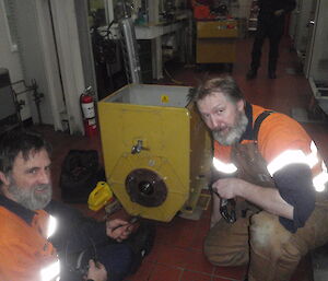 Two expeditioners crouching beside the generator