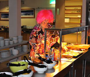 Female expeditoner with pink hair and about to take her meal from the bain marie
