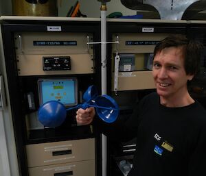 An expeditioner holding the anemometer cups with the monitor registering no wind