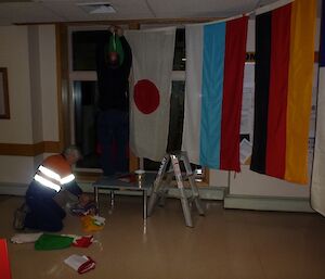 An expeditioner hanging the nations flags in the dining room