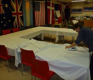 A female expeditioner ironing the tablecloths on the table