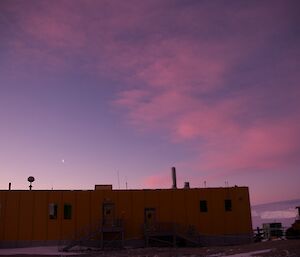 A red sky in the east with the yellow Operations Building in the foreground