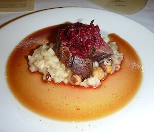 A small piece of venison with beetroot garnush on a bed of hazelnut truffle