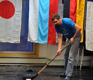 Expeditioner lining up the puck (small block of ice) using an ice hockey stick