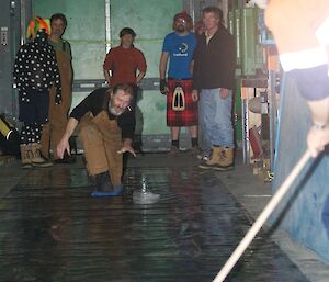 An expeditioner ready to push the curling stone which is a block of ice with a metal handle down to the target