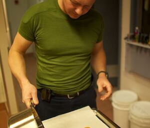 An expeditioner pouring bowling toffee from a saucepan into a tray lined with grease proof paper