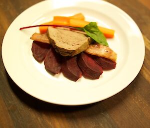 The Main Course-a piece of beef on a slice of bacon sitting on wedges of beetroot and with a beet leaf for decoration